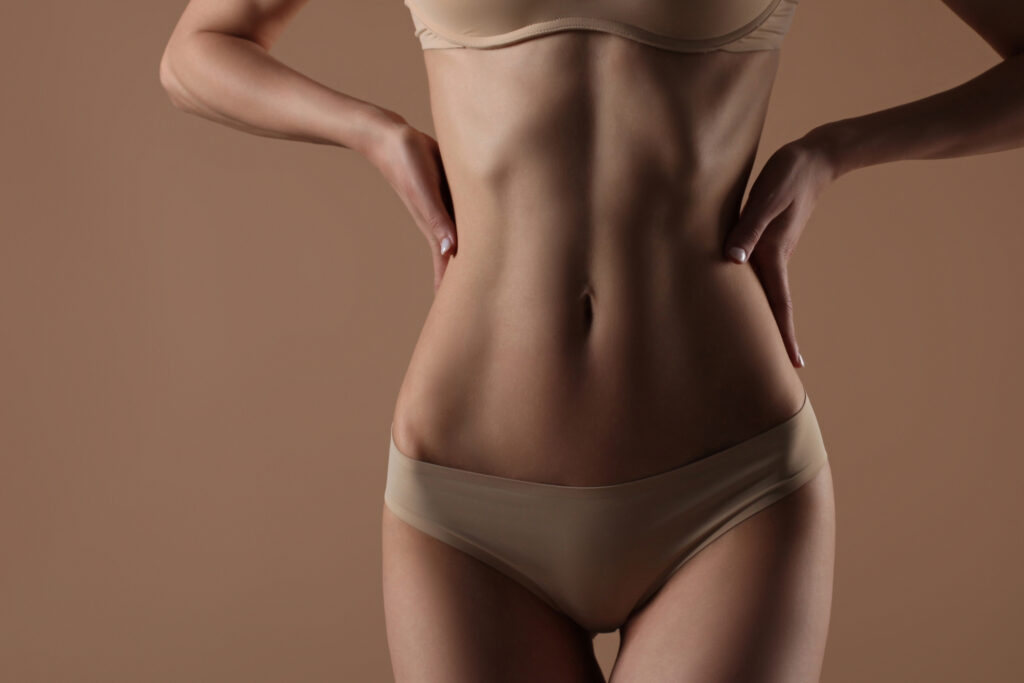 Young woman in nude bikini showing toned figure after tummy tuck surgery recovery with Dr. John Diaz in Beverly Hills, Los Angeles