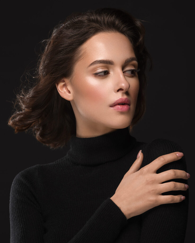 Young woman in black turtle neck sweatshirt showing toned figure after chin augmentation recovery with Dr. John Diaz in Beverly Hills, Los Angeles